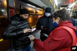 An employee of the Kazan Mayor's Office (right) checks a passenger's QR code on a bus in Kazan on November 22. Tatarstan became the first region in Russia to start requiring proof of vaccination or past illness for access to public transport.