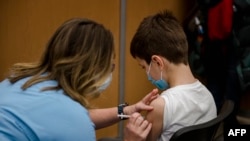 Egy 11 éves fiút oltanak be koronavírus ellen Montreálban 2021. november 24-én