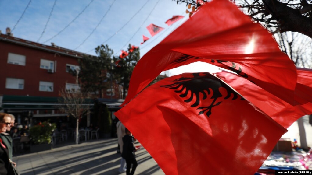 Qytetarët kalojnë pranë disa flamujve të Shqipërisë të vendosur në sheshet e Prishtinës më 28 nëntor 2021. 