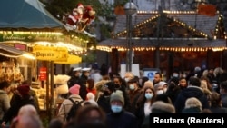Люди в защитных масках на рождественской ярмарке. Франкфурт, Германия, 22 ноября 2021 года.