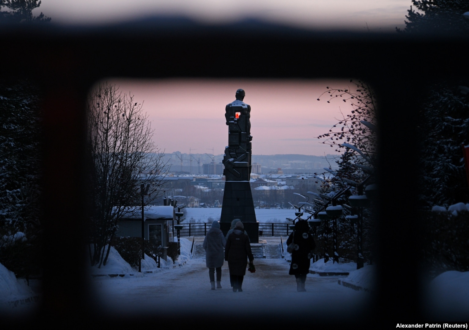 People walk to lay flowers at a monument erected in memory of Kuzbass miners to pay tribute to the miners and rescuers killed in the Listvyazhnaya tragedy on November 26, the day after the explosion.