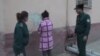  Сотрудники ГУВД города Ташкента заставляют художницу удалить граффити со стены.