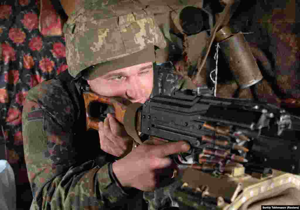 Një pjesëtar i forcave të armatosura ukrainase, duke marrë në shenjë me pushkën e tij, në pozicionet e luftimit, në vijën e ndarjes, pranë qytetit të Donetskut, që kontrollohet nga rebelët, në Ukrainë. (16 prill 2021)