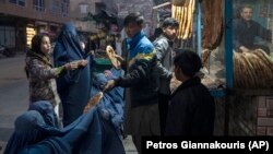 تعدادی از زنان و کودکان فقیر در کابل در مقابل یک نانوایی منتظر دریافت خیرات استند