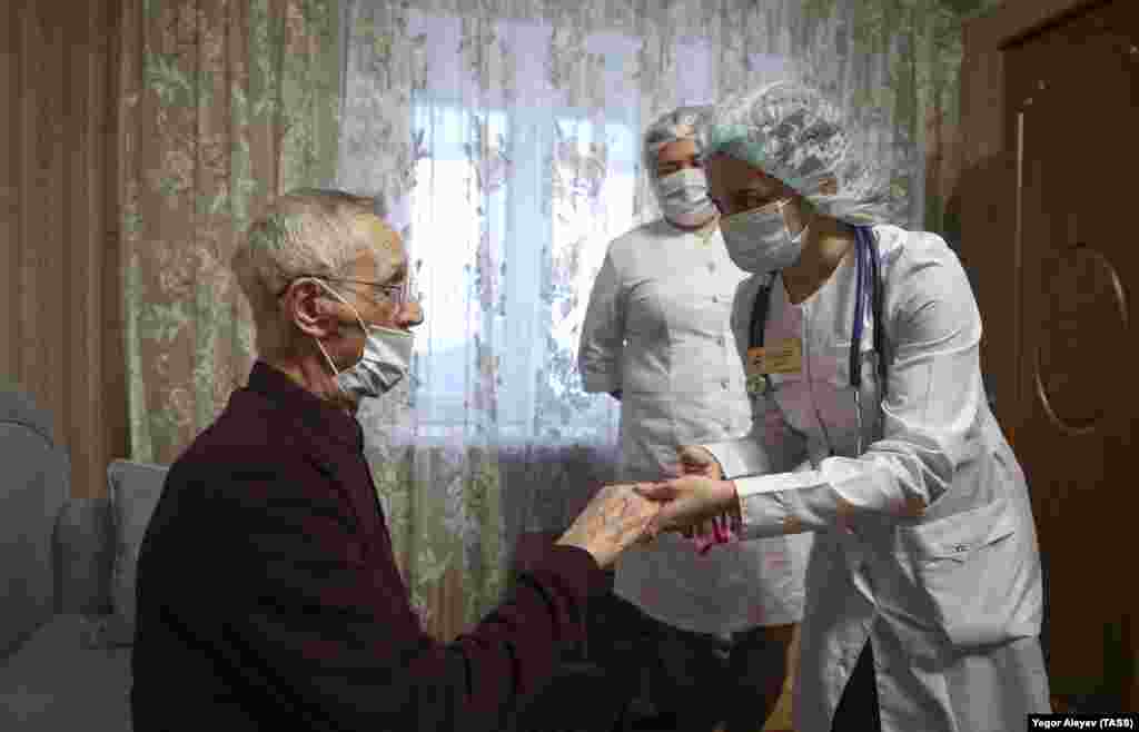 Një infermiere duke ia kontrolluar një të moshuari nivelin e oksigjenit në gjak, para se t&#39;ia jepte atij një vaksinë kundër COVID-19, gjatë një vizite në shtëpinë e tij, në Kazan, Rusi, 2 dhjetor.