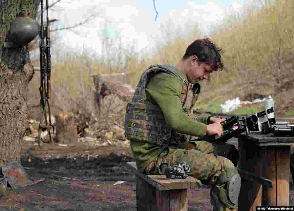 Një pjesëtar i forcave të armatosura ukrainase, duke pastruar një armë, në pozicionet e luftimit, në vijën e ndarjes, pranë qytetit të Donetskut, të kontrolluar nga rebelët, në Ukrainë. (21 prill)