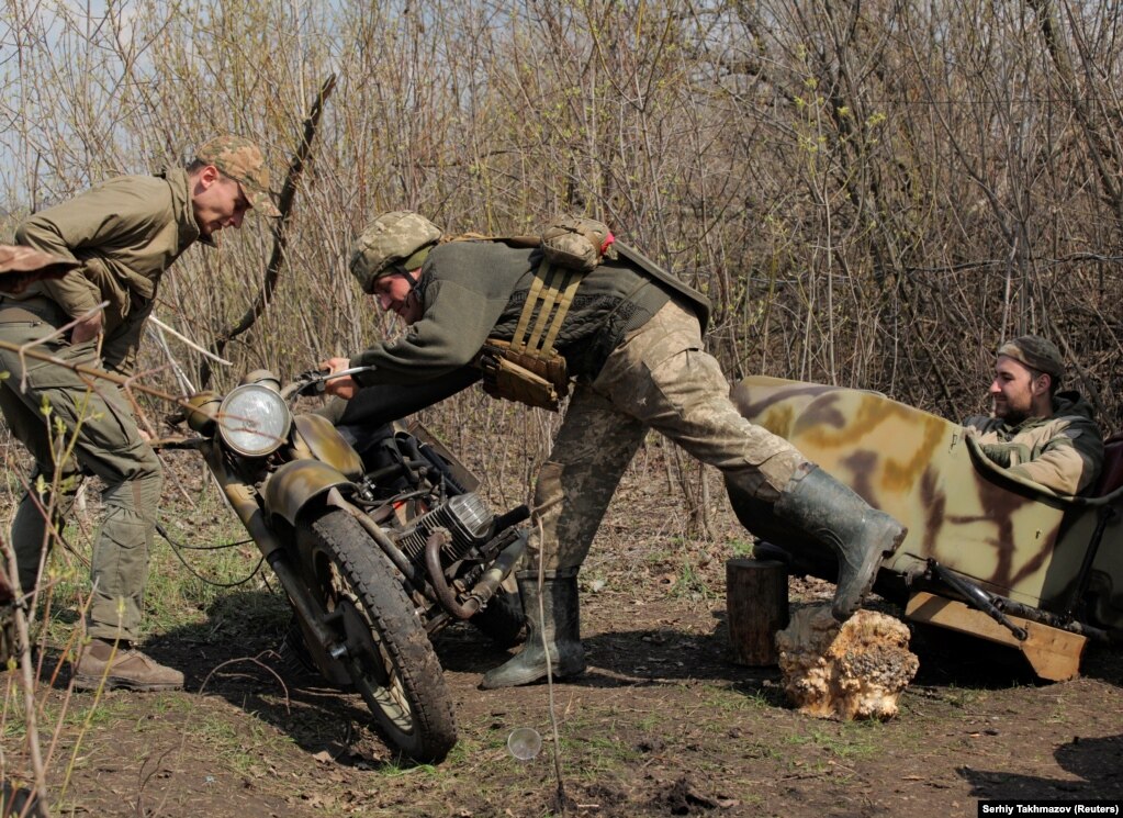 Pjesëtarët e forcave të armatosura ukrainase, duke e rregulluar një motoçikletë, në pozicionet e luftimet, në vijën e ndarjes, pranë qytetit të Donetskut, të kontrolluar nga rebelët, në Ukrainë. (21 prill)