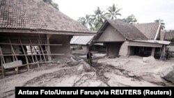 Čovek stoji ispred uništene kuće posle erupcije vulkana Semeru u indonežanskoj provinciji Java, 5. decembar 2021.