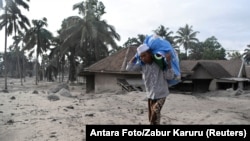 Meštanin sela Sumber Wuluh u provinciji Java nosi stvari u vreći nakon što mu je kuća uništena u erupciji vulkana Semeru, 5. decembar 2021.