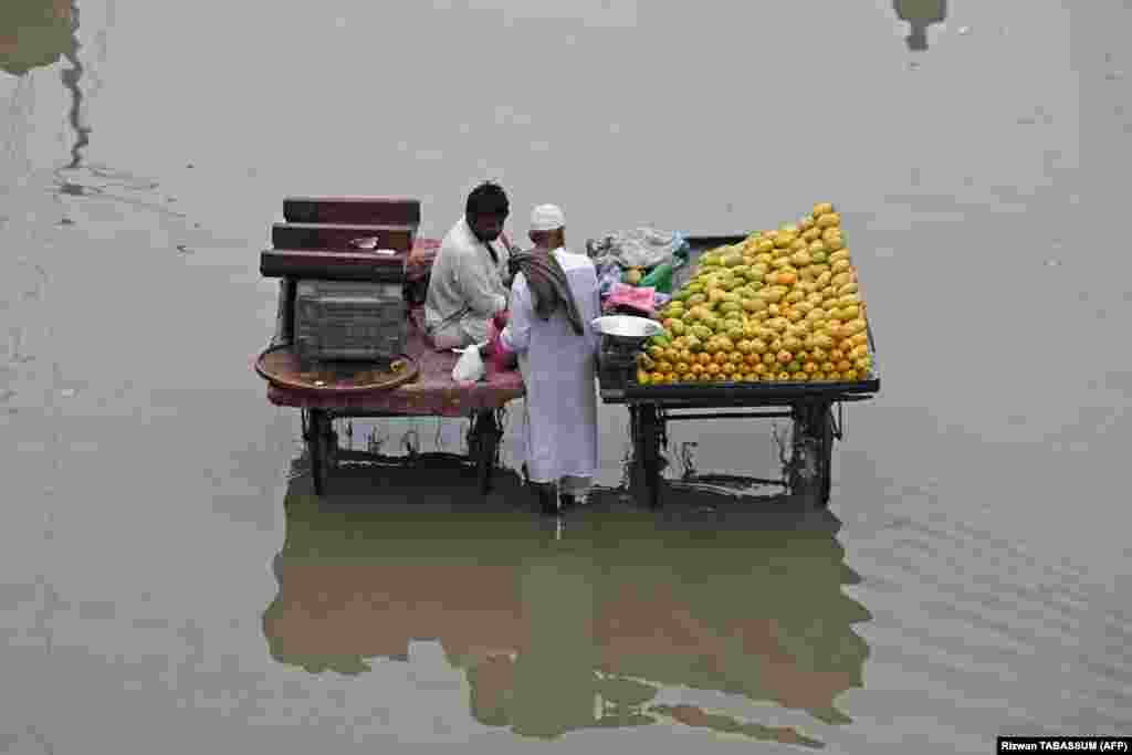 Fruit vendors stand on a flooded street in Karachi, Pakistan.&nbsp;