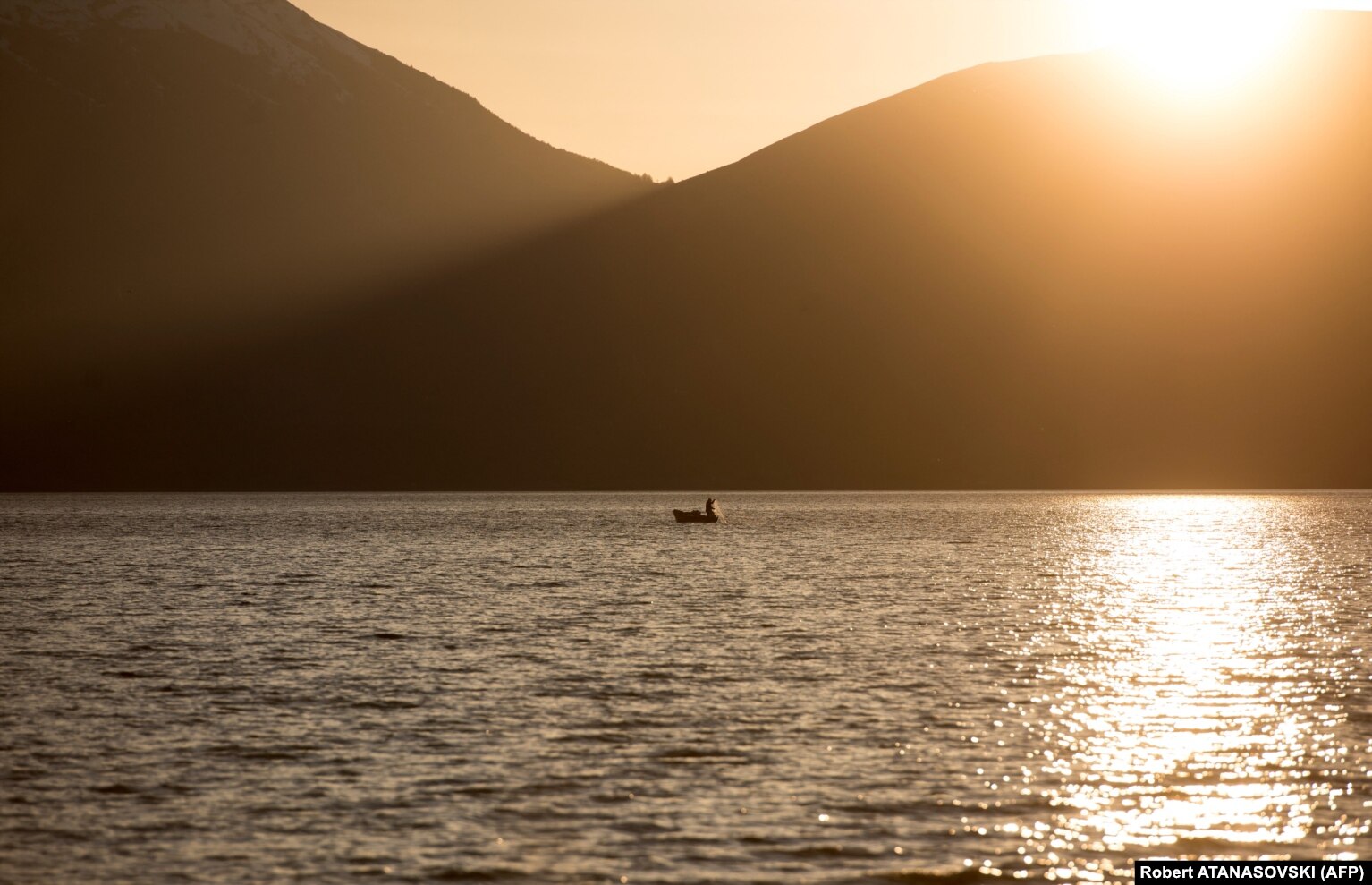 Një peshkatar shijon qetësinë e Liqenit të Prespës një perëndim dielli.