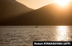 Një peshkatar shijon qetësinë e Liqenit të Prespës një perëndim dielli.