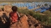 Dijete sjedi na vrhu brda s pogledom na izbjeglički kamp u blizini granice Čada i Sudana, 9. novembra 2023.