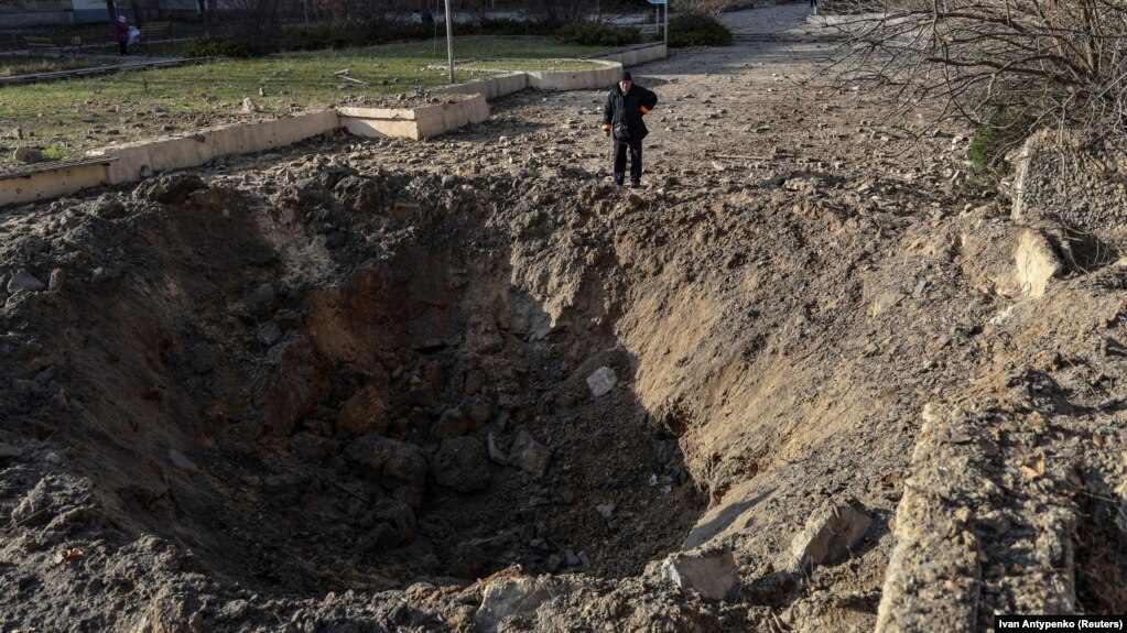 Місцевий житель дивиться на воронку на місці російського ракетного удару, Херсон, 5 грудня 2023 року