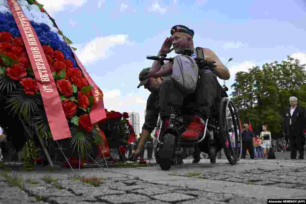 A Russian veteran salutes next to a monument to Soviet soldiers killed in action in Afghanistan during the Soviet invasion of 1979-89, marking the annual Combat Veterans Day at Poklonnaya Hill War Memorial Park in Moscow on July 1.