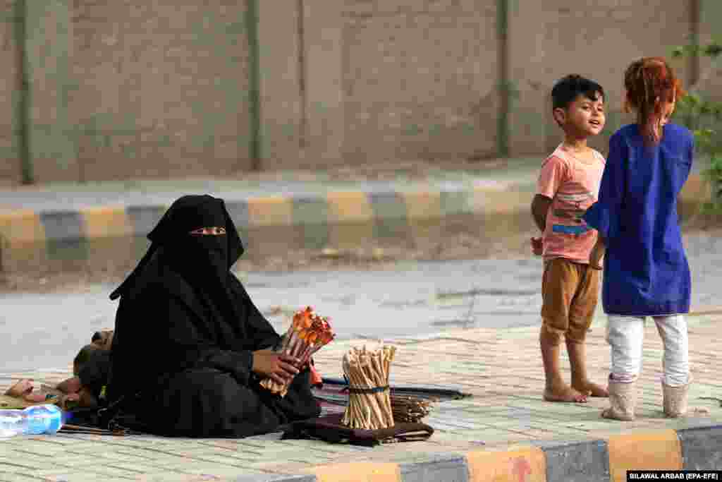 A woman works on a roadside next to her children in Peshawar, Pakistan.