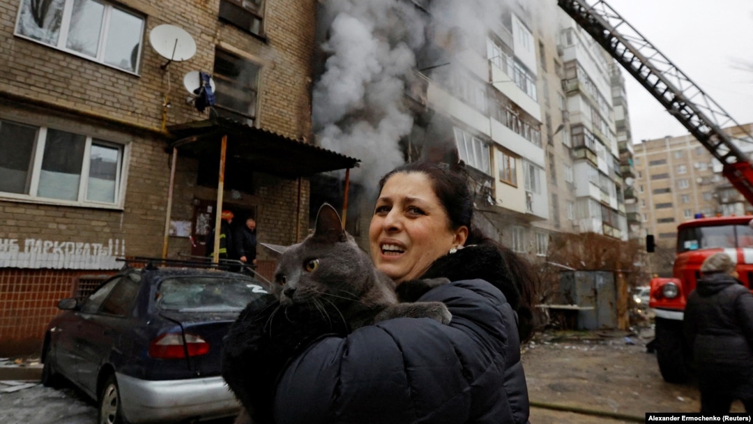 A woman holds her cat, which was carried by a firefighter out of an apartment building damaged by Russian shelling in Donetsk, Russian-controlled Ukraine, on December 19.