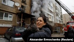 A woman holds her cat, which was carried by a firefighter out of an apartment building damaged by Russian shelling in Donetsk, Russian-controlled Ukraine, on December 19.