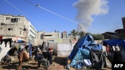 Палестинци, които живеят палатки, на фона на дима след ракетен удар в Хан Юнис