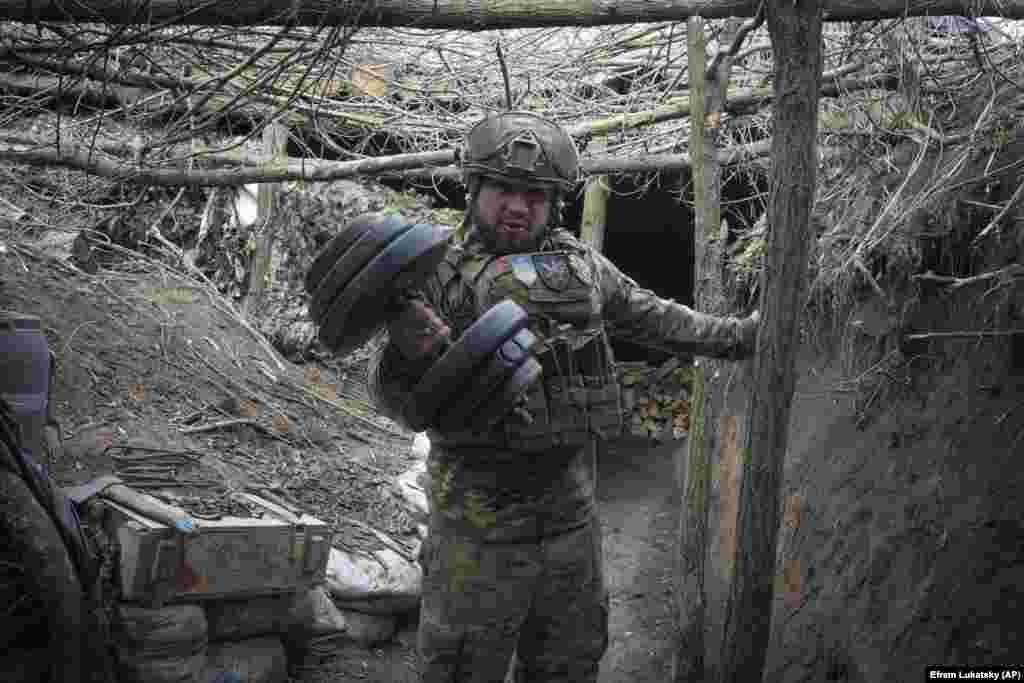 A Ukrainian soldier with a dumbbell in the trench he calls home. &nbsp;