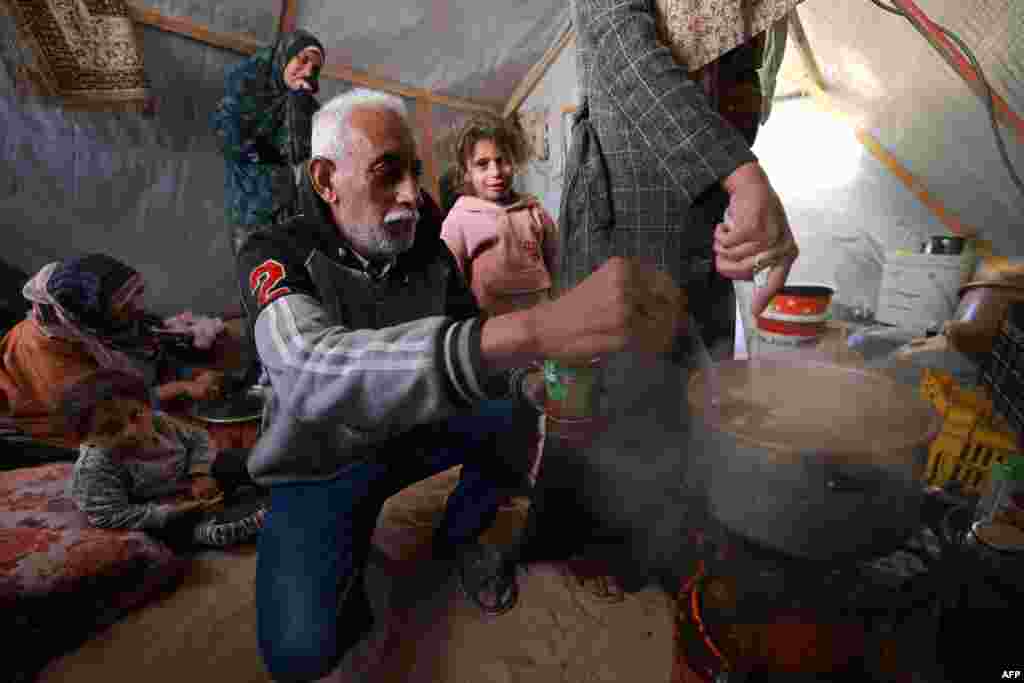 Një familje e zhvendosur duke përgatitur ushqimin për iftar në një tendë në Rafah.