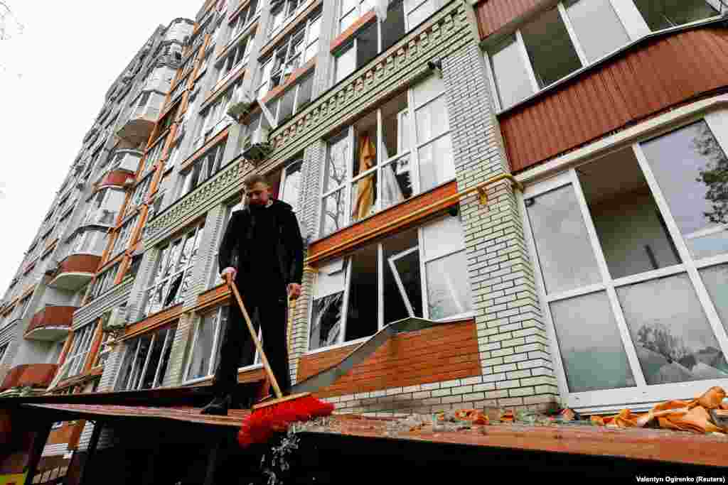 Чоловік прибирає уламки скла на місці ракетного удару, Чернігів