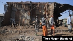 Ljudi stoje pored kuća uništenih u vazdušnom napadu tokom borbe između Etiopskih nacionalnih odbrambenih snaga i snaga Narodnog oslobodilačkog fronta Tigraj, 25. februara 2022.