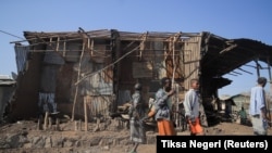 Stanovnici i pripadnici milicije pored kuća uništenih u vazdušnom napadu tokom borbe između Etiopskih nacionalnih odbrambenih snaga i snaga Narodnog oslobodilačkog fronta Tigraj u gradu Kasagita, Etiopija, 25. februar 2022.