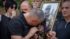 The father of Ihor Voyevodin cries as he holds a photo of his son, who was killed in a battle with Russian troops, during a farewell ceremony at the University in Kyiv on August 25.