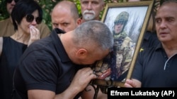 The father of Ihor Voyevodin cries as he holds a photo of his son, who was killed in a battle with Russian troops, during a farewell ceremony at the University in Kyiv on August 25.