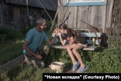 Николай Трищенко во дворе своего дома в деревне Усть-Коса играет с приезжими детьми. Фото: Наталья Лозинская для НВ