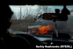 Украинские военные идут мимо горящего автомобиля, сбитого дроном-камикадзе. Окрестности прифронтового города Авдеевка в Донецкой области, ноябрь. Автор: Сергей Нужненко, украинская редакция «Азаттыка».