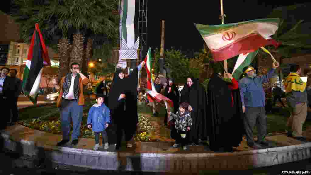 Emberek iráni és palesztin zászlót lengetnek a teheráni Palesztina téren április 14-én kora reggel. Az izraeli hadsereg szerint több mint száz drónt indítottak Iránból, iraki és jordániai biztonsági források több tucatról számoltak be