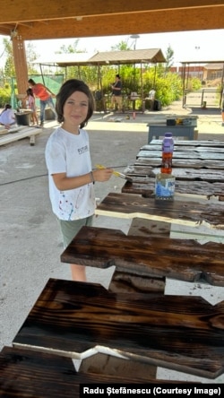 Filipi, një djalë i ri vullnetar, duke i lyer me një tretësirë për ruajtje panelet prej druri të nxjerra nga shtëpia.