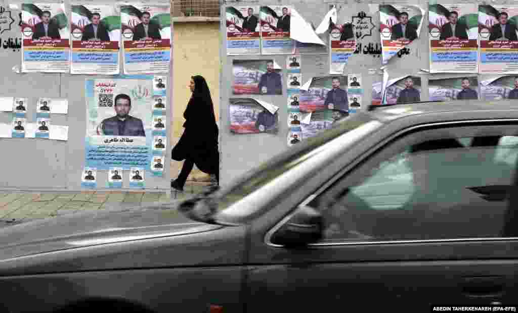 A veiled woman walks past election campaign posters for the upcoming parliamentary elections along a street in Tehran on February 26.