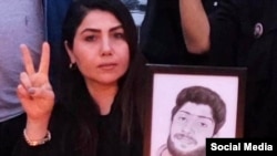 A woman holds a portrait of her son, who was killed during the crackdown on protesters in Iran.