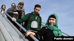 Вывезенные из сектора Газа казахстанцы и члены их семей спускаются по трапу самолёта, который приземлился в Алматы