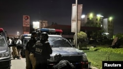 Police officers take positions after a police building was attacked by gunmen in Karachi, Pakistan, on February 17.