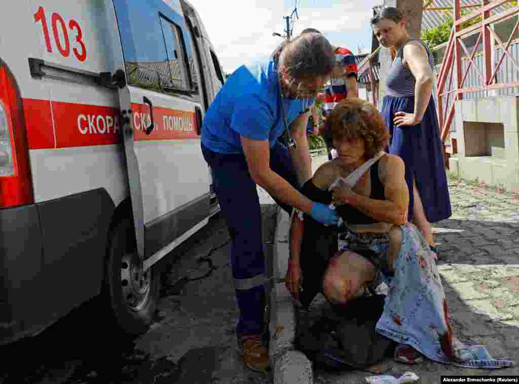 Un paramedic tratează o femeie rănită în timpul bombardamentului.