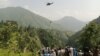 People watch as a soldier descends from a helicopter during a rescue mission to save students stuck in a chairlift in Khyber Pakhtunkhwa Province on August 22.