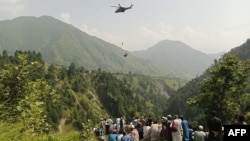 People watch as a soldier descends from a helicopter during a rescue mission to save students stuck in a chairlift in Khyber Pakhtunkhwa Province on August 22.