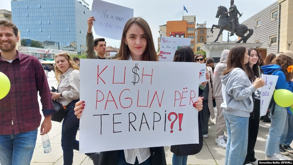 "Kush pagun për terapi?!" shkruhet në pankartën që mban një pjesëmarrëse në marshin për shëndetin mendor.