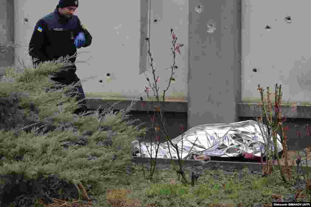 A Ukrainian rescuer stands next to a body of a person killed in the missile strike.