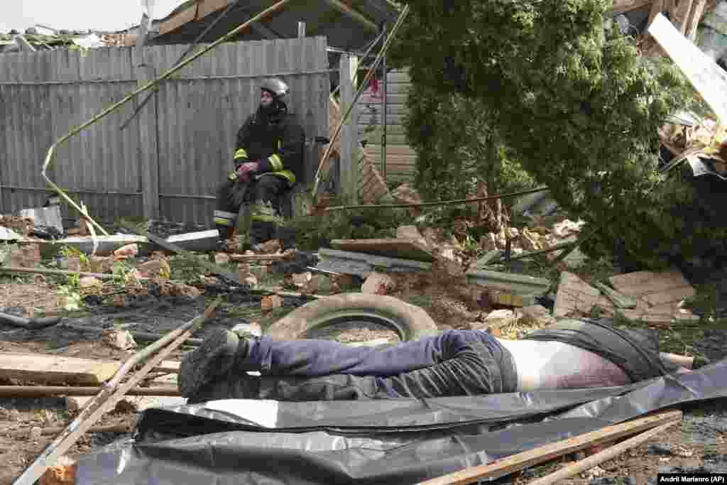 A rescue worker sits in front of a body of a local resident who was killed by Russian rocket attack in Tsyrkuny, Ukraine on May 18.