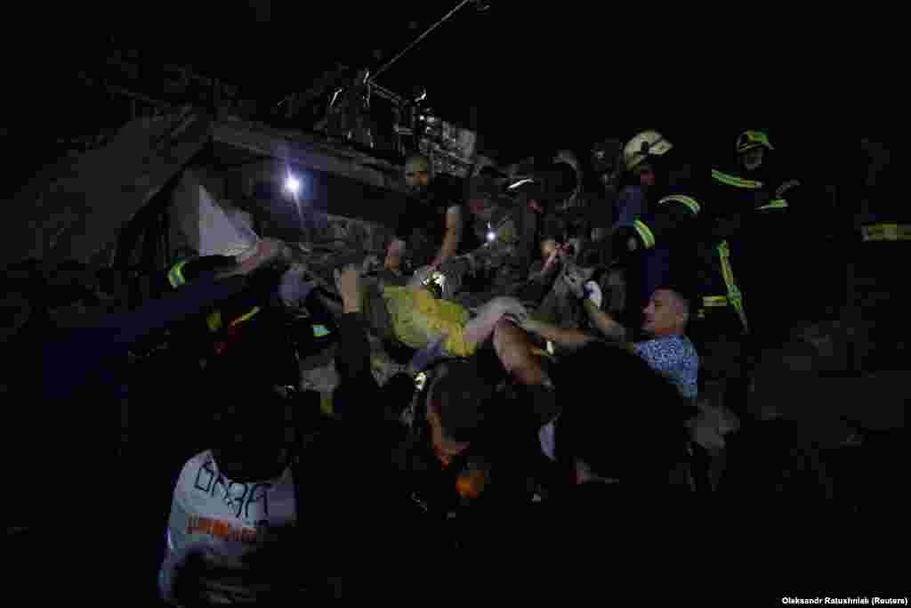 Rescuers and volunteers carry a woman rescued from the rubble. The head of the Donetsk military administration, Pavlo Kyrylenko, told Ukrainian television that missiles struck when the area was crowded with civilians.