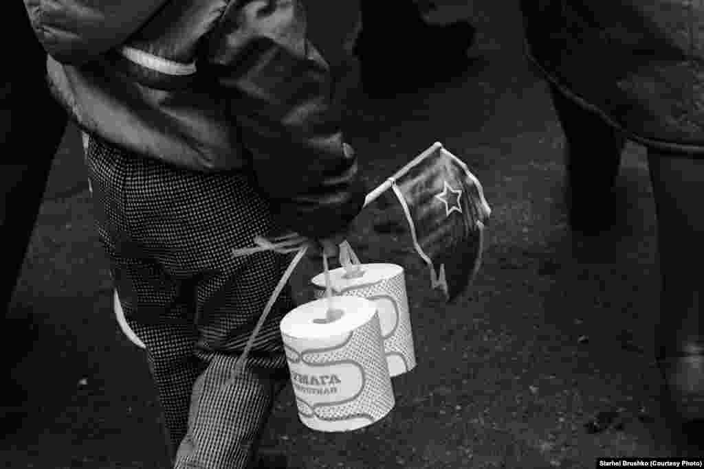 Дзіця нясе рулёны дэфіцытнай туалетнай паперы падчас шэсьця ў гонар Кастрычніцкай рэвалюцыі, 7 лістапада 1988 году&nbsp;