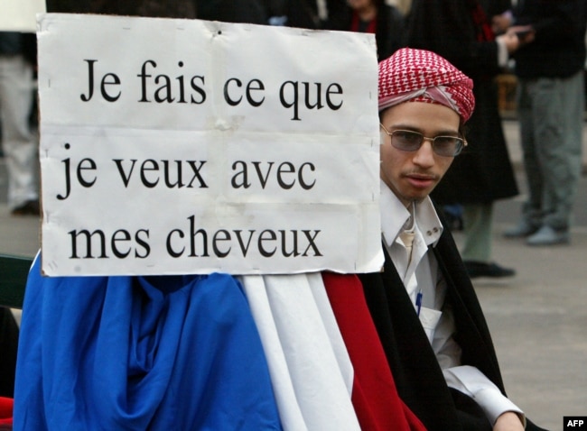 مخالفان قانون لائیسیته در فرانسه با پلاکاردی که روی آن نوشته: «با موهایم هر کاری که بخواهم می‌کنم»