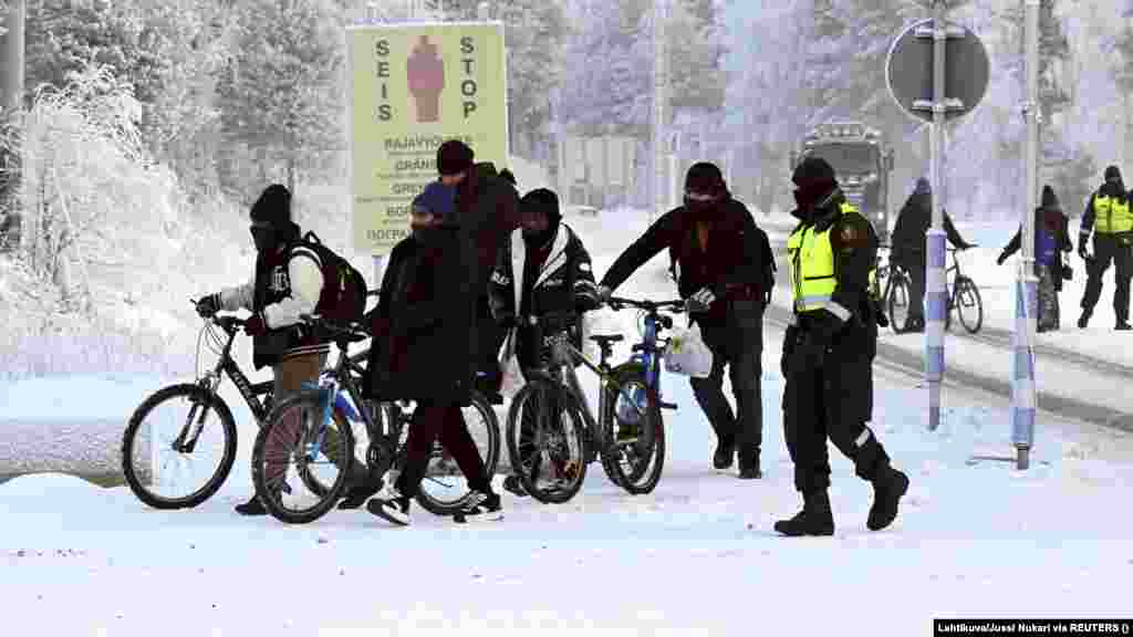 Финские пограничники ведут мигрантов с велосипедами к пограничному переходу в Салле, 21 ноября. Большинство мигрантов &mdash; молодые люди в возрасте от 20 до 30 лет, но есть и семьи с женщинами и детьми, согласно данным пограничной службы и фотографиям новостных агентств&nbsp;