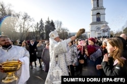 Митрополит Кишинівський та всієї Молдови Володимир кропить освяченою водою вірян біля собору в центрі Кишинева. Січень 2023 року