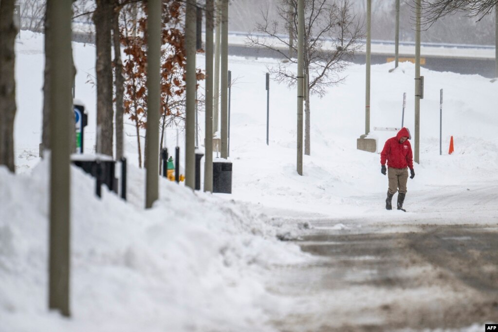 Një burrë duke ecur në një rrugë të pastruar nga bora, Ajova.